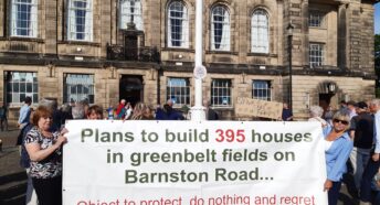 People protesting against a housing development with a banner